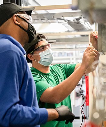 Electrical student in mask with teacher